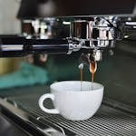 White Ceramic Mug on Espresso Machine Filling With Brown Liquid